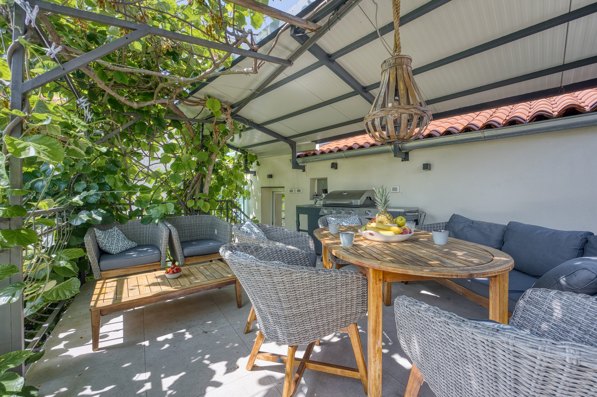 25 qm Sonnenterrasse mit Gas-BBQ, Lounge und Esstisch unter Kiwi-Bewuchs