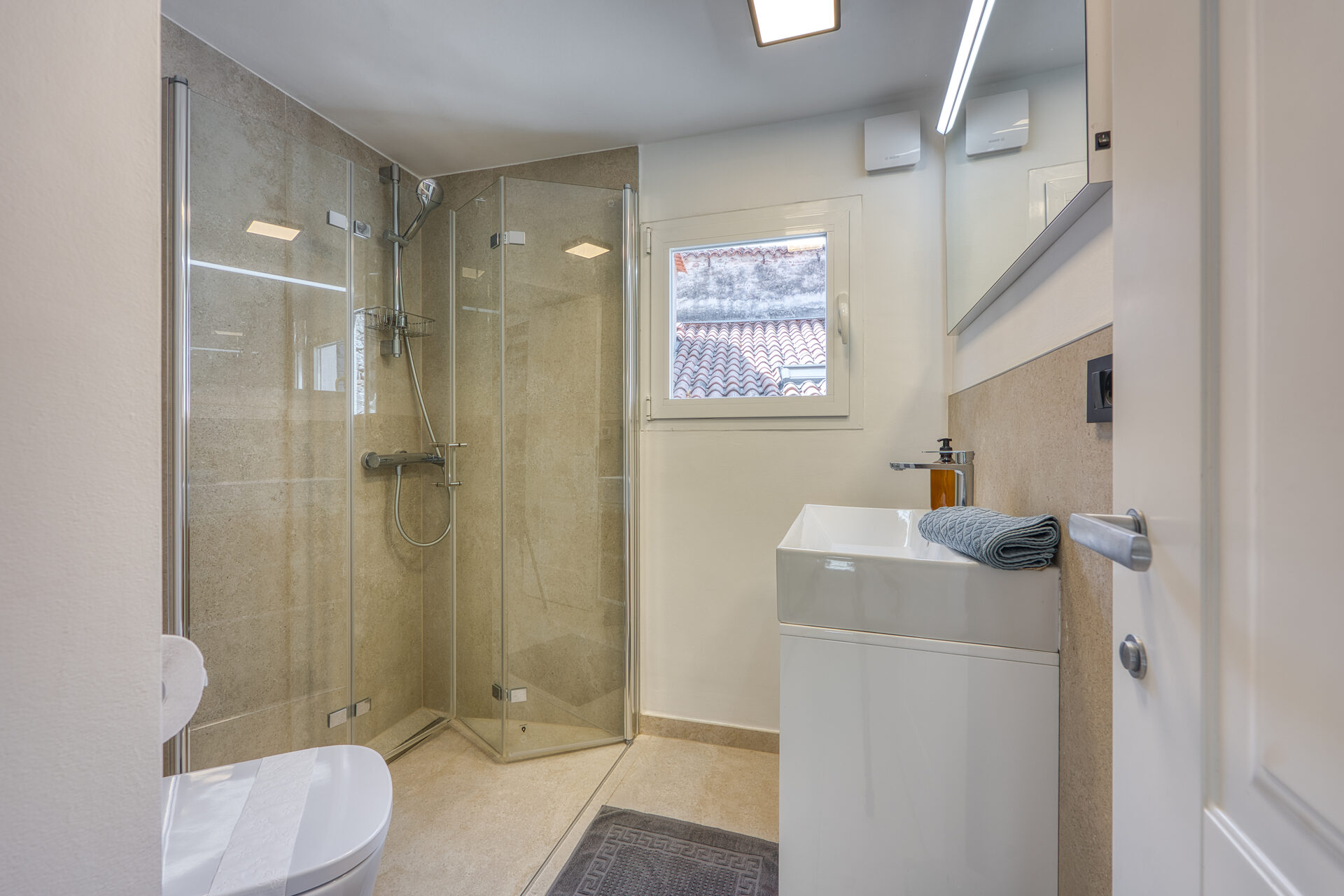 Hauptbadezimmer mit ebenerdiger Glasdusche und Naturstein-Wand
