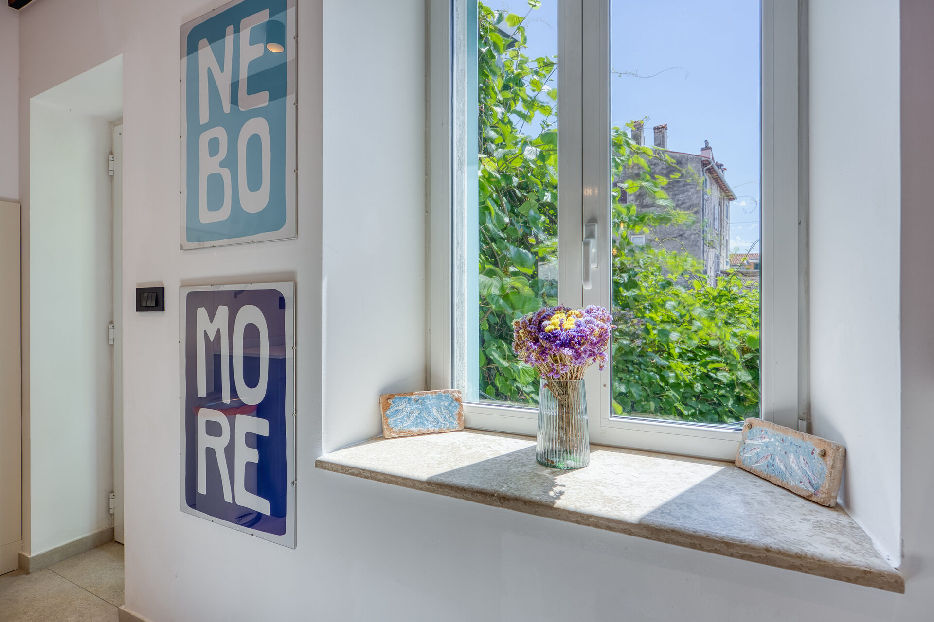 NEBO MORE Kunstdruck am Fenster mit Blick in den begrünten Innenhof