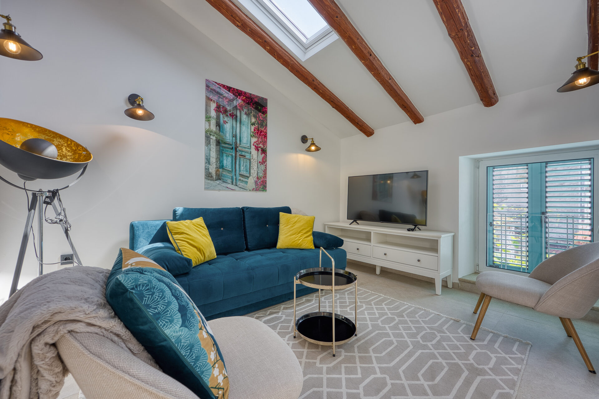Wohnzimmer mit Flatscreen, blauem Samtsofa und Skylight im Dachgeschoss