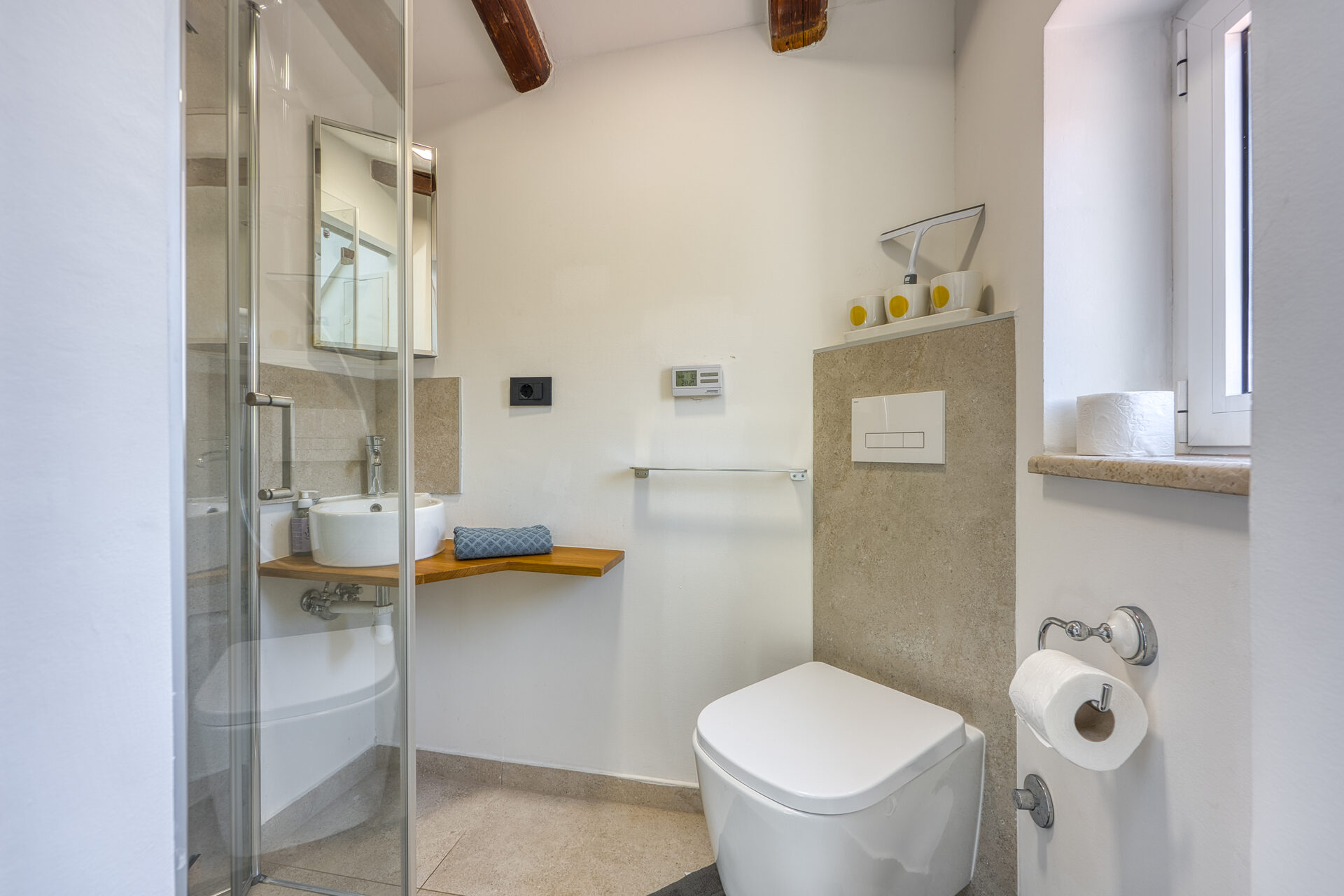 Zweites Badezimmer mit Glasdusche und Holzwaschtisch im Obergeschoss